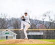 Young baseball pitcher on the mound, preparing to throw under a bright sky on a sunny day.