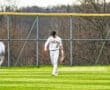 A baseball player in striped uniform walks on green grass field, preparing for play during a game.