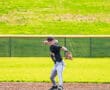 Young baseball player in action, throwing a ball on a sunny day at the field, showcasing athleticism and focus.