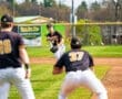 A baseball player on the mound prepares to pitch while teammates stand ready on the field. Bright sunny day.