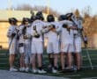 Lacrosse team huddles on the field, symbolizing teamwork and strategy before a game.