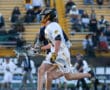 High school lacrosse players running on the field during a match, showcasing athleticism and team spirit.