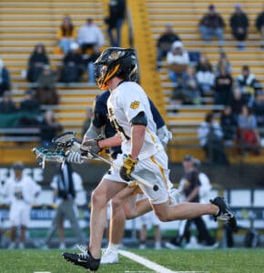 High school lacrosse players running on the field during a match, showcasing athleticism and team spirit.