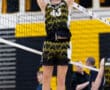 A young volleyball player in mid-air prepares to set the ball during a game, showcasing athleticism and focus.