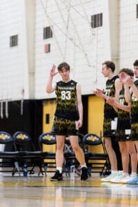 North Allegheny basketball player, number 83, waves to the crowd as teammates applaud during a game.