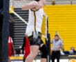 Male volleyball player celebrates after a point during a high school match, with teammates and referees in the background.