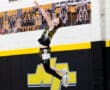 Young basketball player leaping for a shot in a gym with vibrant yellow and black team colors.