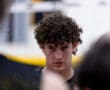 Focused young male volleyball player with curly hair, concentrating during practice in a gym setting.