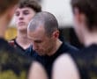Coach discussing strategy with players during a basketball huddle, focusing on teamwork and preparation for the game.
