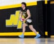 A volleyball player from North Allegheny prepares to serve during a game in a sports gymnasium.