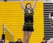 High school volleyball player jumps to set a ball during a match, showcasing skills in a vibrant gym.