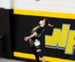 Young volleyball player jumping to serve a ball in a gymnasium with black and yellow decor, showcasing athleticism.
