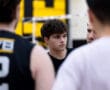 Team huddle during a volleyball practice, focusing on a player listening intently in a sports gym setting.