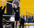 High school volleyball player #43 preparing to set the ball during a match, with fans and coaches in the background.