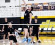 Players in black uniforms compete in a volleyball match, showcasing teamwork and athletic skills on the court.