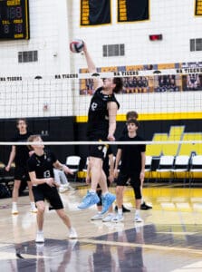 Players in black uniforms compete in a volleyball match, showcasing teamwork and athletic skills on the court.