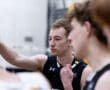 Volleyball team member strategizing during a practice session in an indoor gym setting, focused on teamwork.