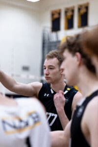 Volleyball team member strategizing during a practice session in an indoor gym setting, focused on teamwork.
