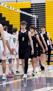 High school volleyball players shake hands after a match, showcasing sportsmanship in a competitive environment.