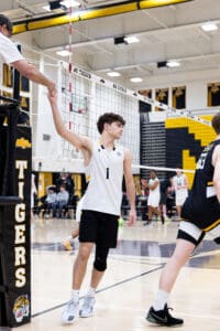 A volleyball player shakes hands with the referee during a game, surrounded by teammates and spectators.
