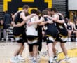 Basketball team huddled together, showing teamwork and strategy before their game on a court with black and yellow colors.