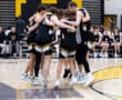 High school basketball team huddling together for a team meeting on the court before a game.