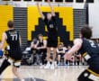 Player 43 jumps to set the volleyball during a competitive match, with teammates and opponents in the background.