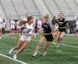 Girls playing flag football during a competitive match on a green field, showcasing teamwork and athleticism.
