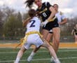 Two female athletes compete in a flag football game, showcasing dynamic gameplay on a grassy field.