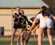 High school girls' flag football game with players in action on the field, one preparing to pass the ball.