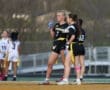 Two female athletes in black jerseys strategizing on the field during a flag football game, showcasing team spirit.