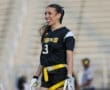 Cheerful female player in a black sports uniform, smiling on the field during a flag football game.