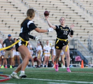 Female flag football player throws a ball during a game, showcasing athletic skill and teamwork on the field.