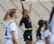 Girl celebrating a successful play in flag football, raising her arms in excitement while teammates observe.