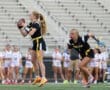 Girls' flag football game: player prepares to pass while teammate moves to receive the ball on the field.