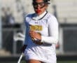 Lacrosse player in a white Tigers uniform running on the field with a lacrosse stick, focused and determined.
