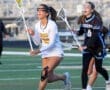 High school girls' lacrosse match with players in action on the field, showcasing teamwork and competitive spirit.