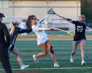 High school girls' lacrosse match with players in action on the field, showcasing teamwork and athleticism.
