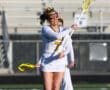 Girl lacrosse player in action on the field, wearing team colors and gear, preparing to make a play during practice.