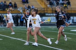 High school girls' lacrosse players compete on the field, showcasing athleticism and teamwork in an exciting match.