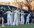 Girls' lacrosse game at sunset, players in uniforms preparing for play on the field, showcasing teamwork and athleticism.