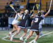 High school girls' lacrosse players competing on the field during an evening match, showcasing teamwork and athleticism.