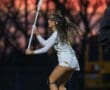 Female lacrosse player in action during sunset, showcasing athleticism and focus on the field.