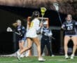 Female lacrosse players compete in an evening match, showcasing speed and teamwork on a vibrant field.
