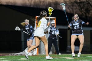 Female lacrosse players compete in an evening match, showcasing speed and teamwork on a vibrant field.