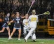 High school girls' lacrosse game action at sunset, with players from the Raiders and Tigers in competitive play.