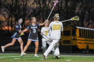 High school girls' lacrosse game action at sunset, with players from the Raiders and Tigers in competitive play.