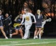 Lacrosse game in action at dusk, featuring players in motion on the field, showcasing teamwork and athleticism.
