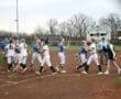 High school softball players shake hands after a game, showcasing sportsmanship on the field.