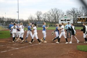 High school softball players shake hands after a game, showcasing sportsmanship on the field.